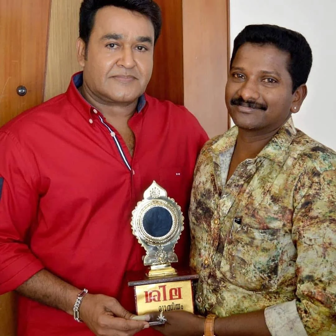 Santhosh handing an Aranmula kannadi mounted on a plinth reading ‘Sila Museum’ in Malayalam to the actor Mohanlal.